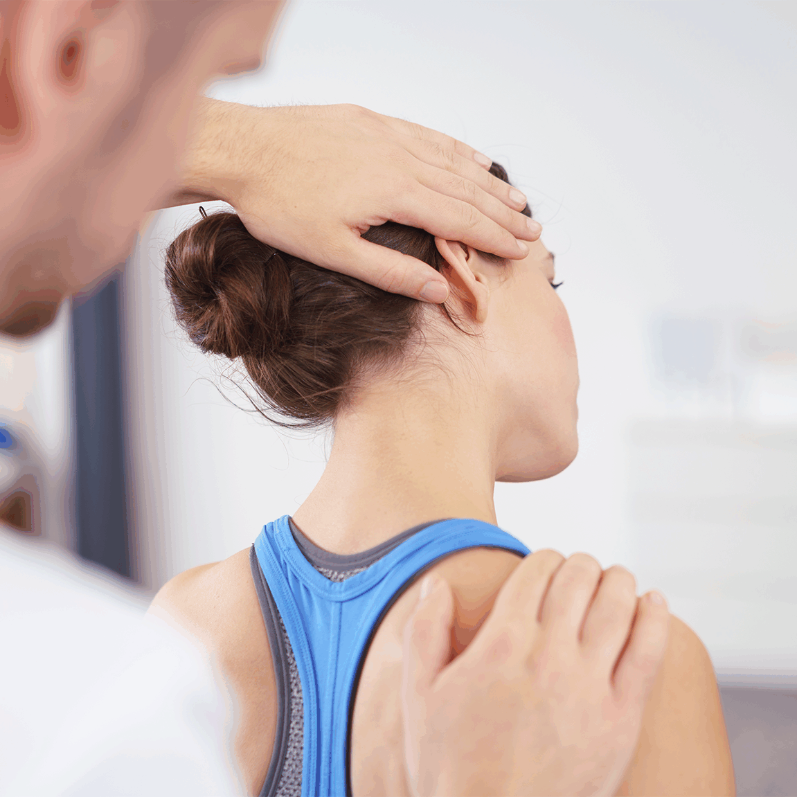 Ein Physiotherapeut führt eine Nacken- und Schultermobilisation bei einer Patientin durch, die ein blaues Sporttop trägt.